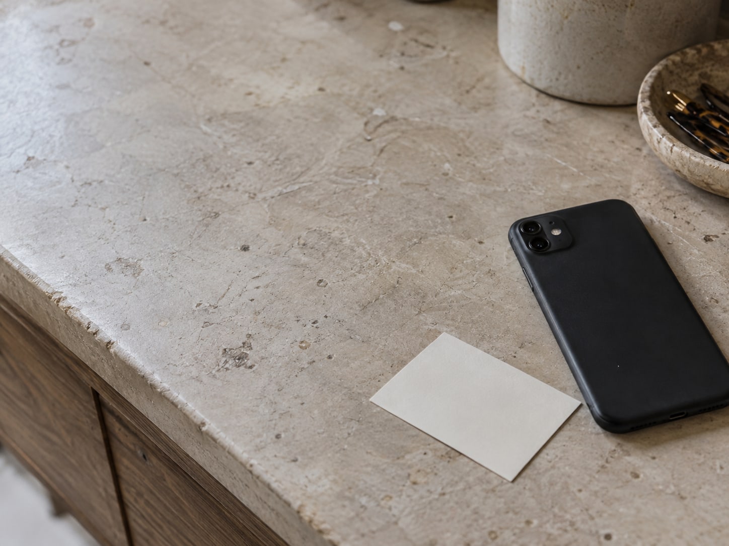 A closed phone lying face down next to a small paper appointment card on a salon counter.