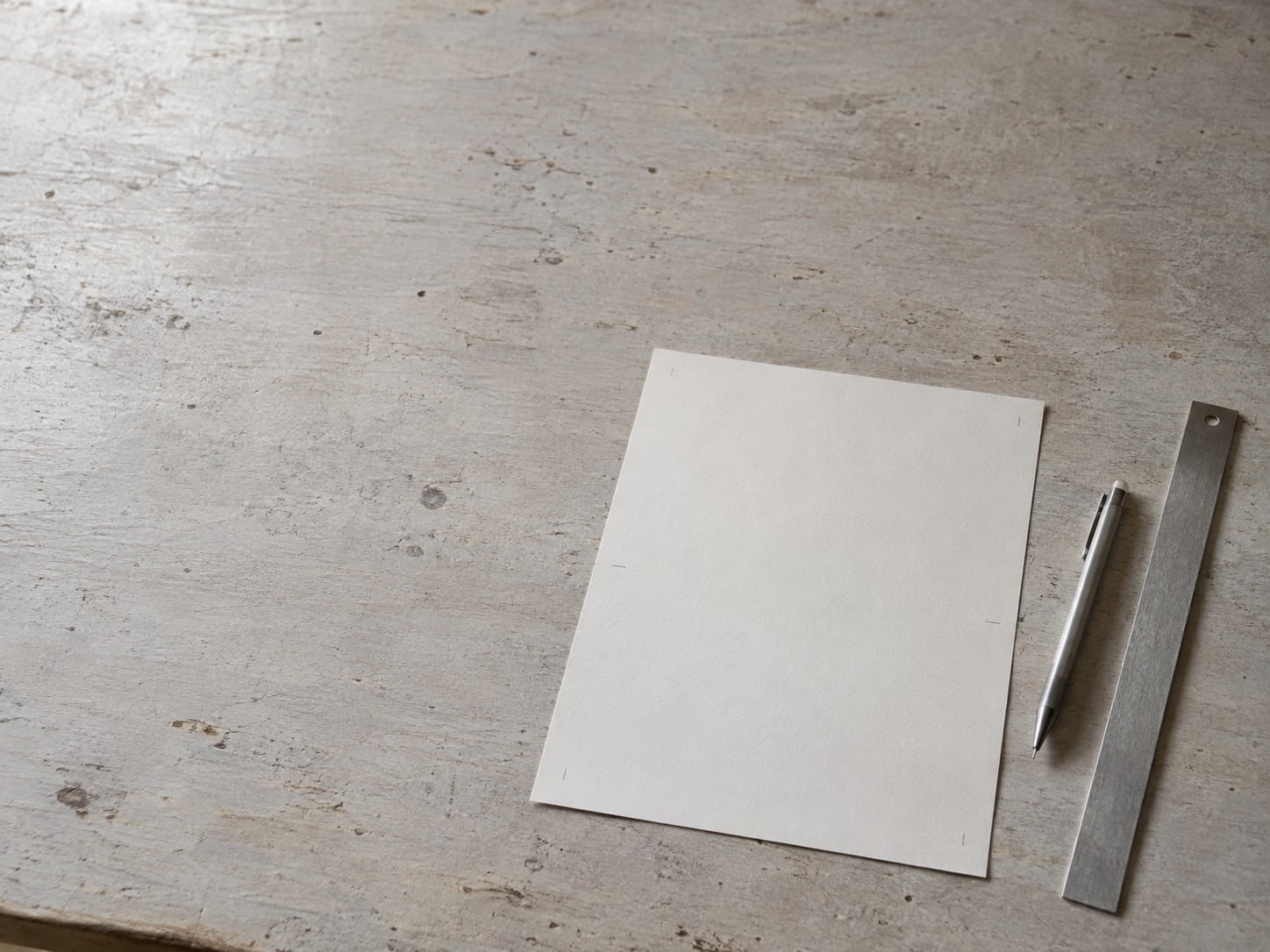 A single sheet of paper with only faint pencil ticks in the margin, beside a pen and a ruler.