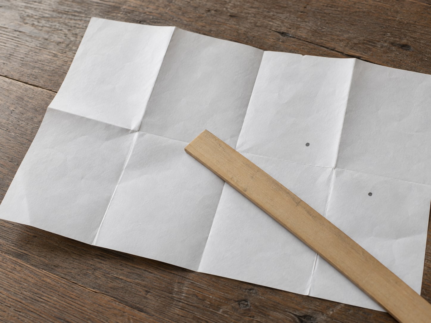 Una regla limpia tendida sobre un mapa de papel de una ciudad pequeña, con dos puntos pequeños de lápiz marcados.