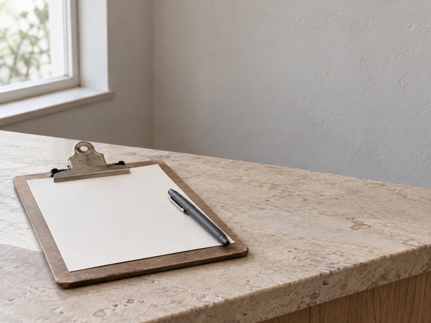 A blank paper sign-up card and a closed pen resting on a clipboard on a reception counter.
