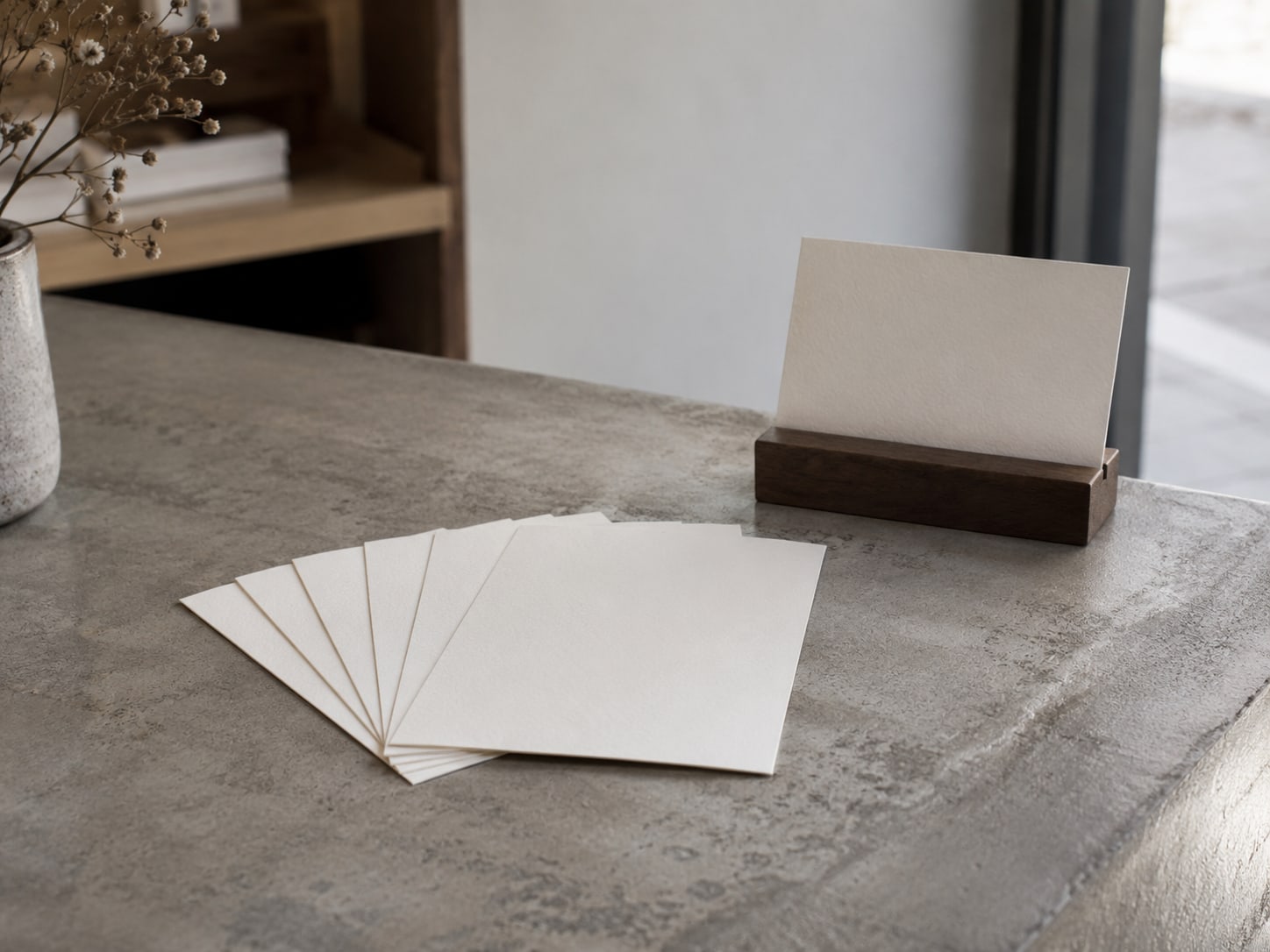 Several blank thank-you cards fanned out on a shop counter beside a small standing card holder.