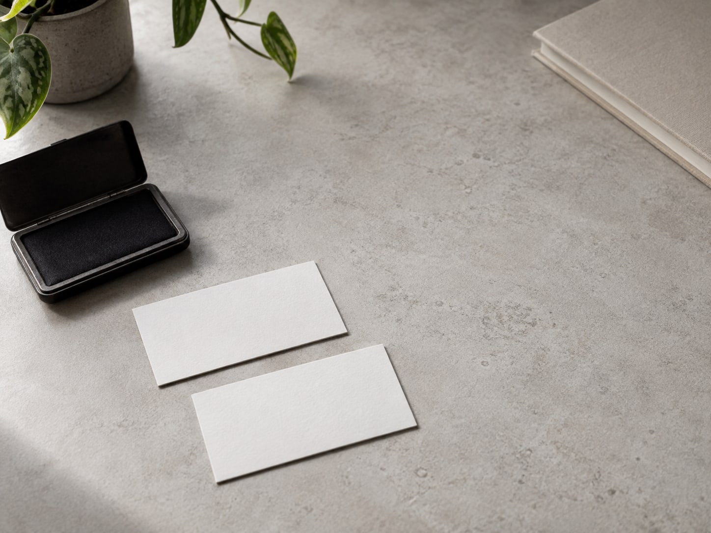 Two business cards face down next to a small stamp pad on a desk.