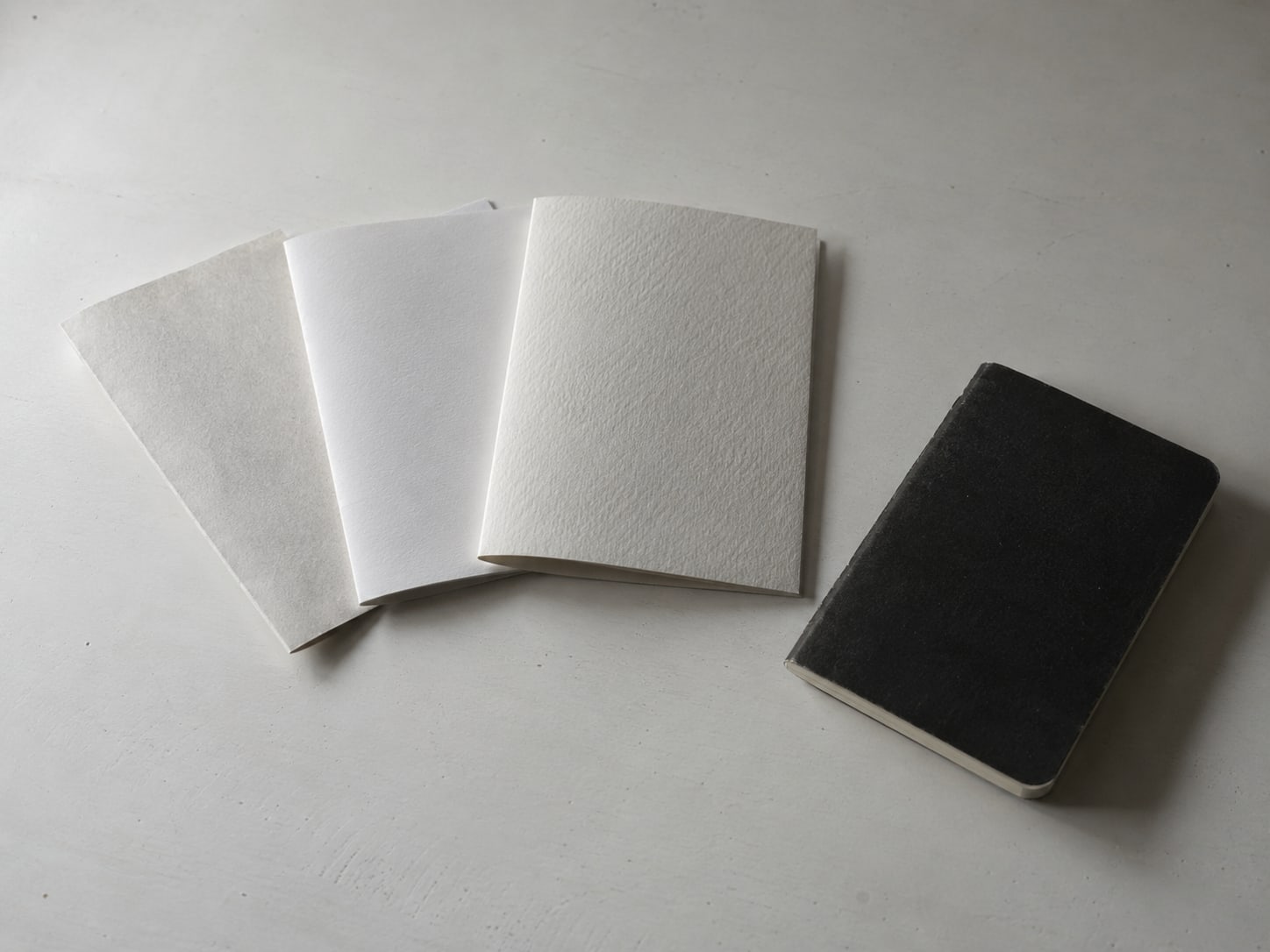 Three folded paper quotes of different thicknesses fanned out on a desk beside a small closed notebook.