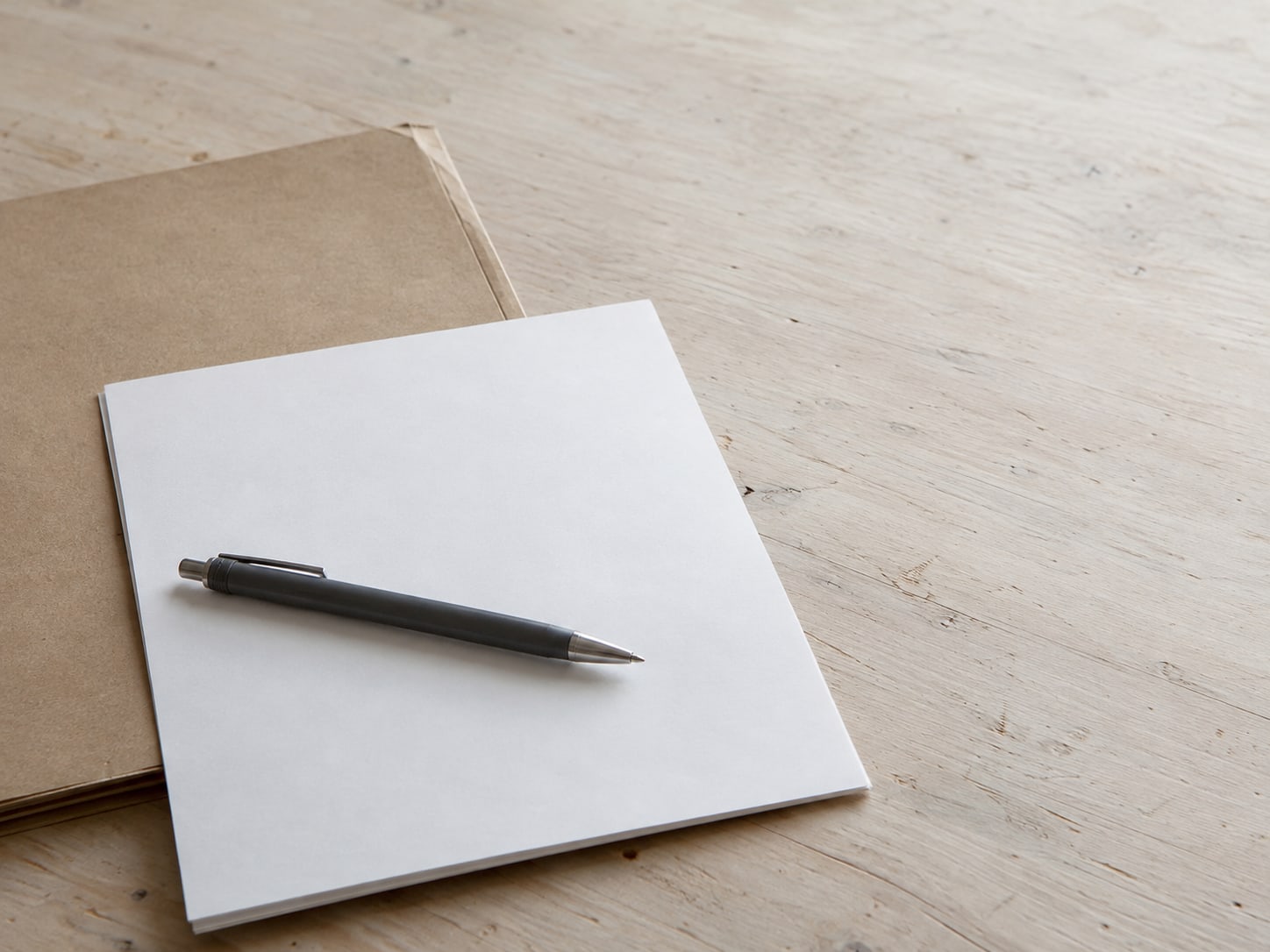 A signed paper form with a pen laid across it next to a closed folder.