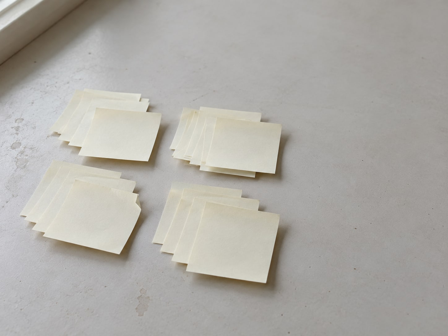 Rows of small sticky notes sorted into four groups on a pale table.