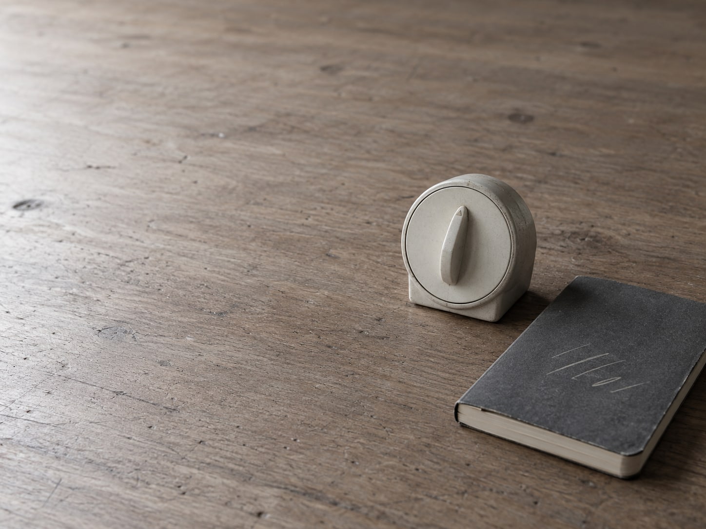 A kitchen timer and a small notebook of pencil tally marks on a plain table.