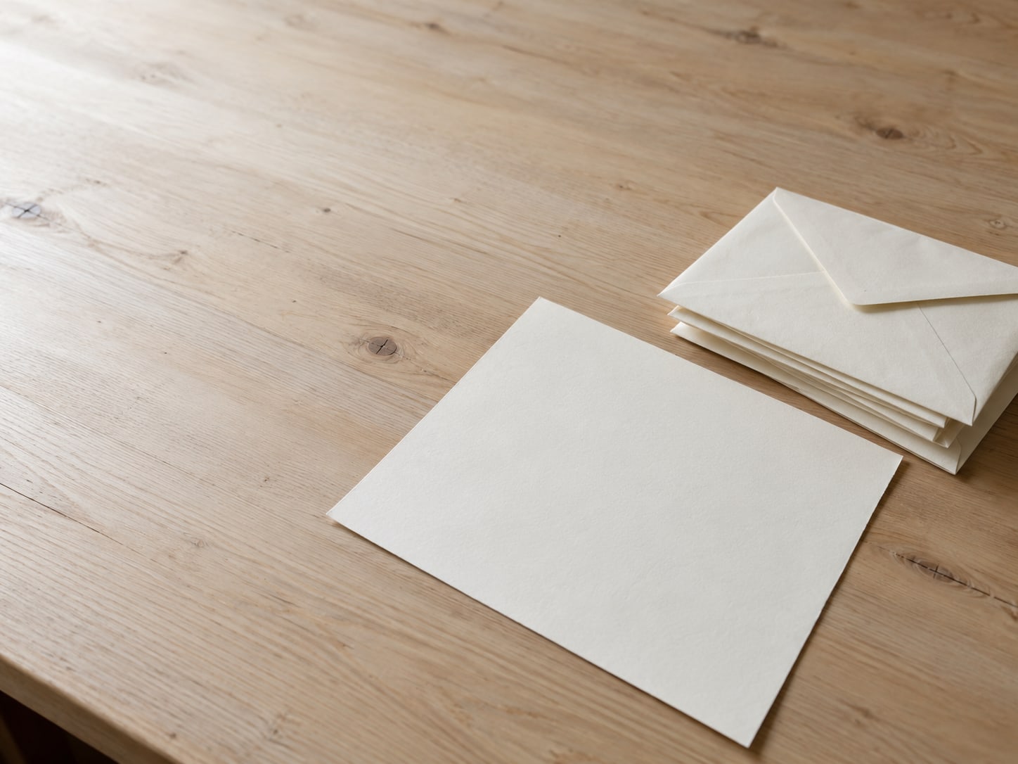 A single blank sheet of paper on a clean desk next to a stack of unopened envelopes.