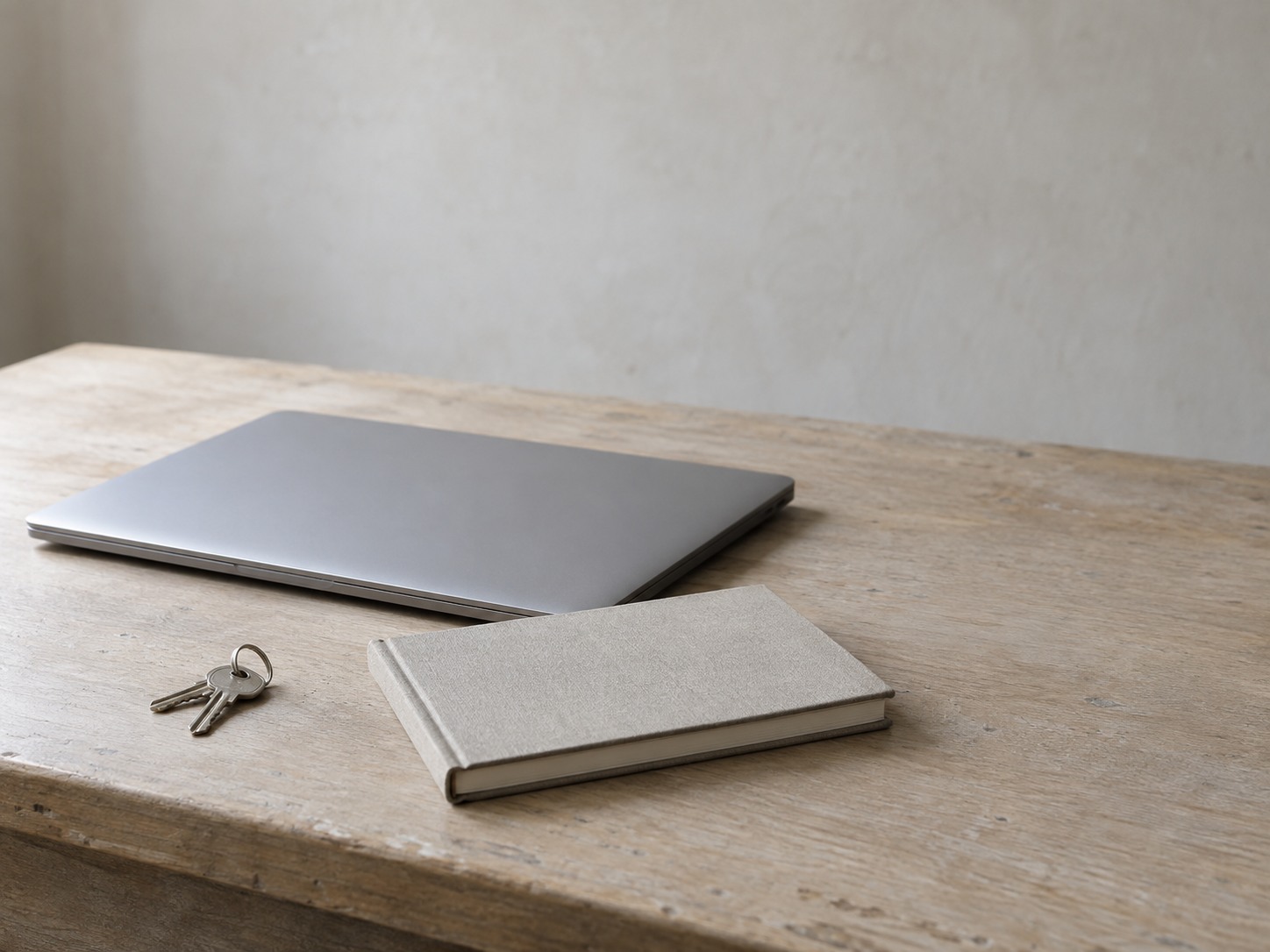 A ring of shop keys, a blank appointment book and a closed laptop arranged on a tidy front desk in soft morning light.