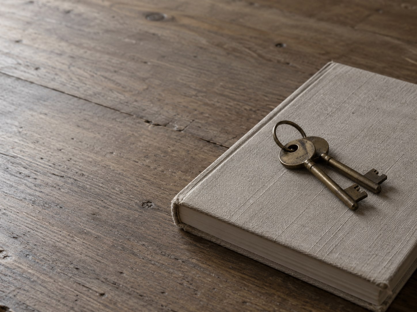 Two identical brass keys on a ring resting on a closed notebook.
