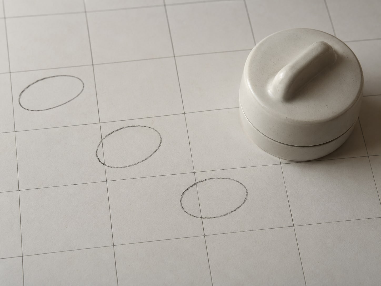 A paper calendar page with a few days circled in pencil next to a small kitchen timer.