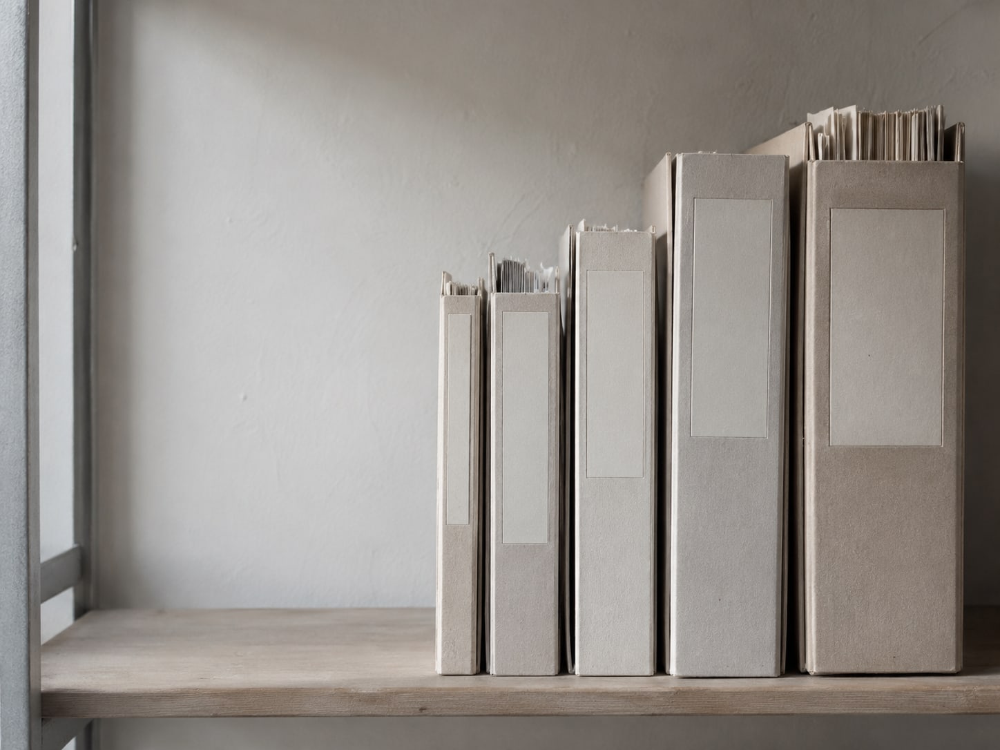A tidy row of blank folders in different thicknesses on a shelf, each with an empty label.