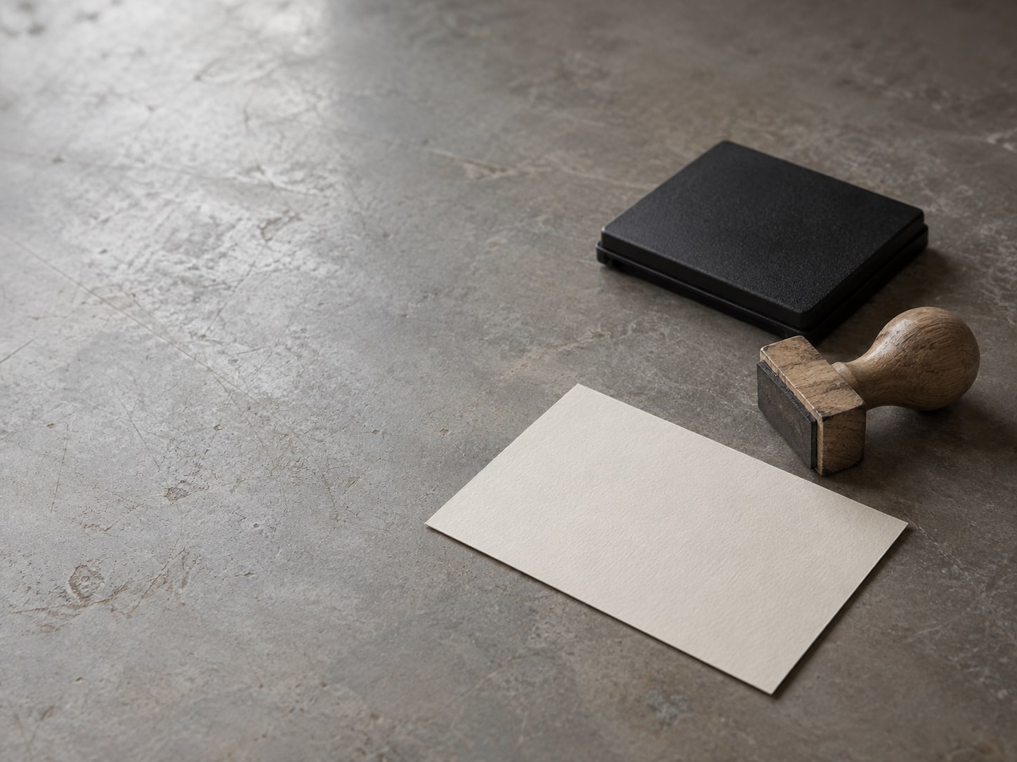 A small wooden stamp lying next to an ink pad and a blank card on a plain table.