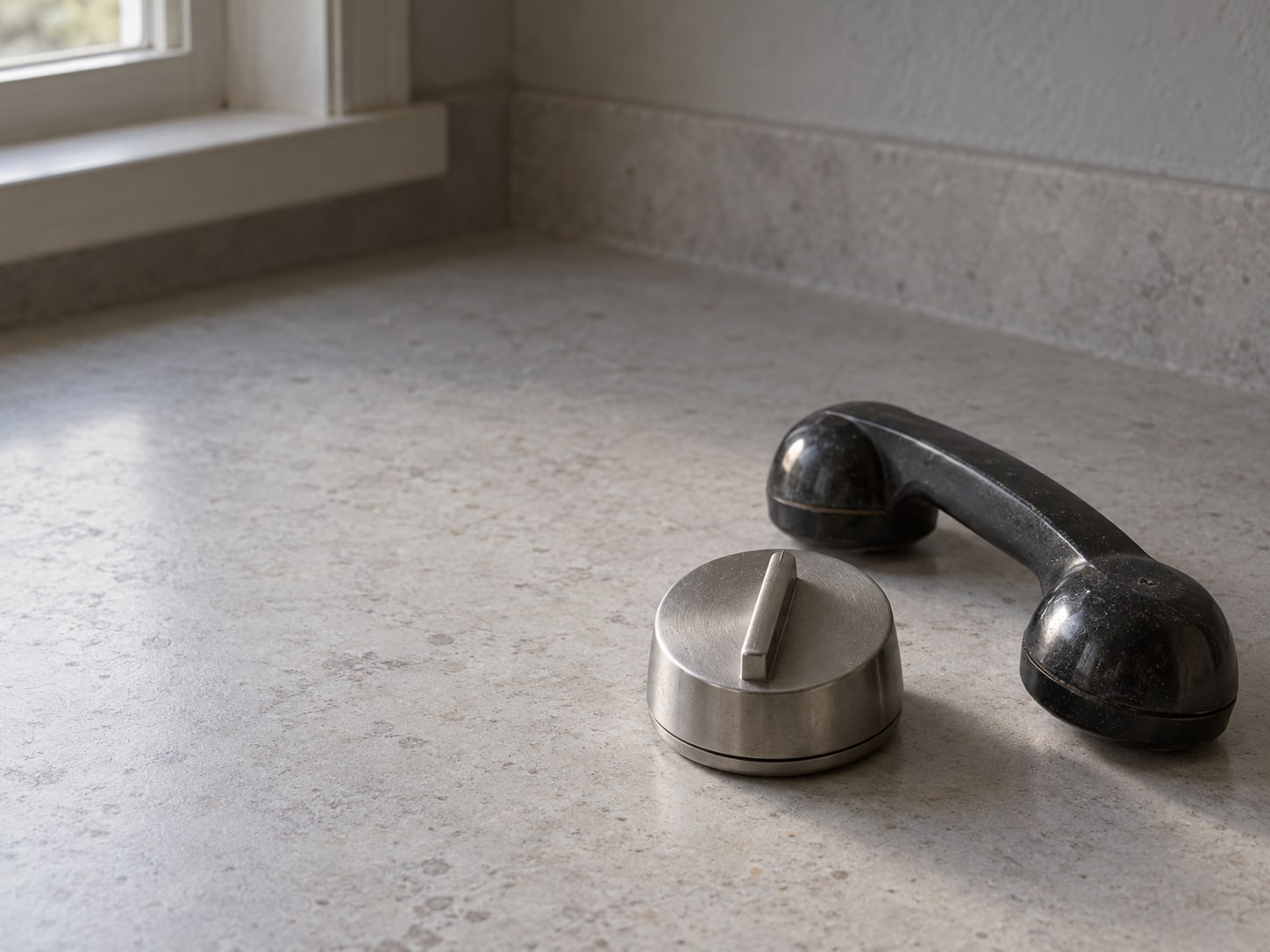 A kitchen timer set on a counter beside a closed telephone handset.