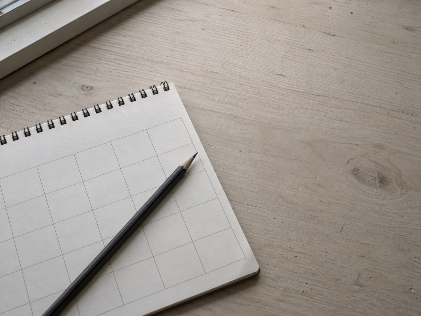A calendar page with several unmarked days and a pencil laid across it on a desk.