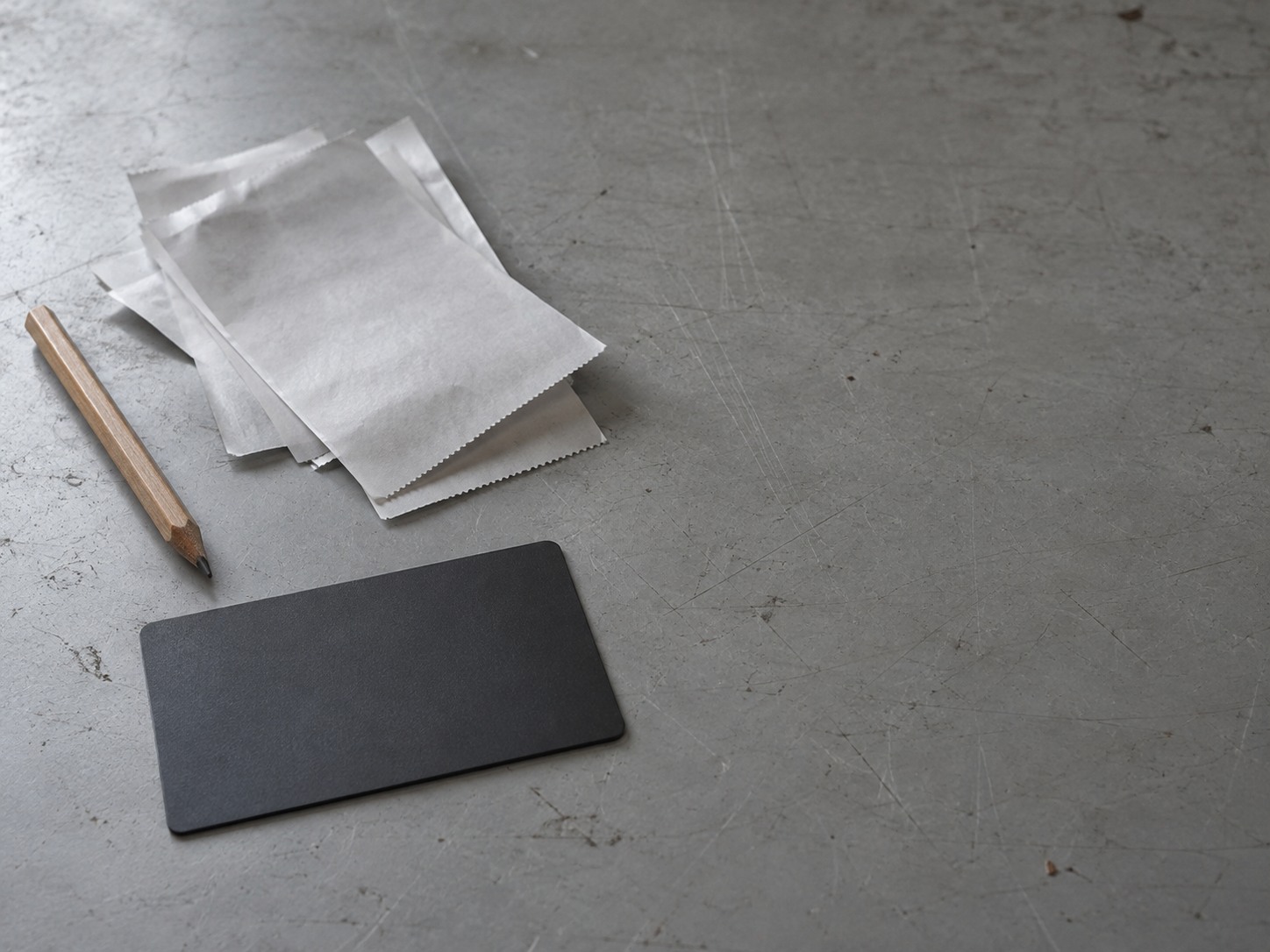 A payment card lying face down beside a small pile of blank paper receipts and a pencil on a desk.