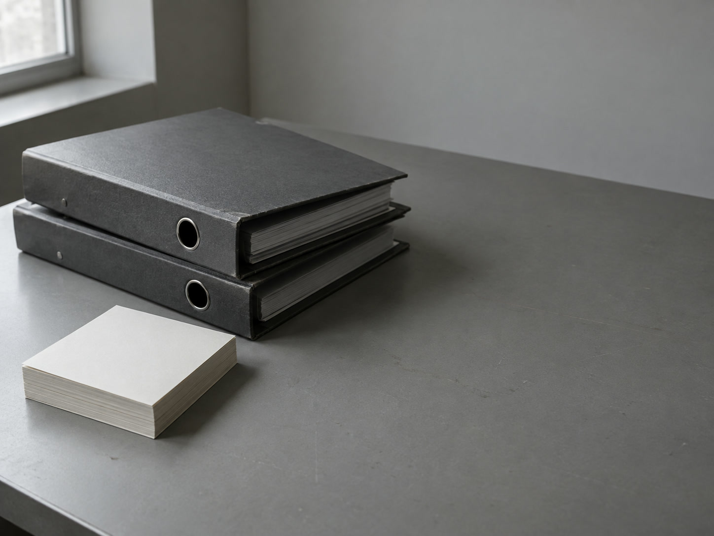 Two ring binders and a small stack of blank index cards squared neatly on an empty office desk.
