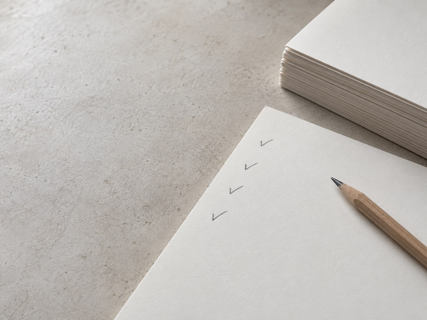 A printed page with several pencil check marks in the margin beside a tidy stack of papers.