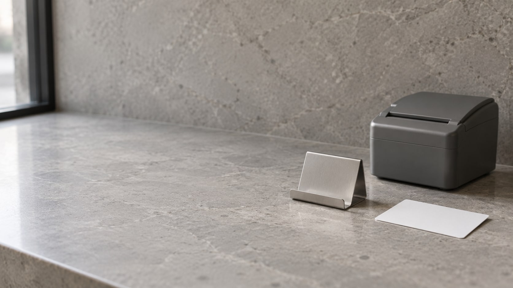 A small card stand on a clean service counter beside a closed receipt printer and a blank card.