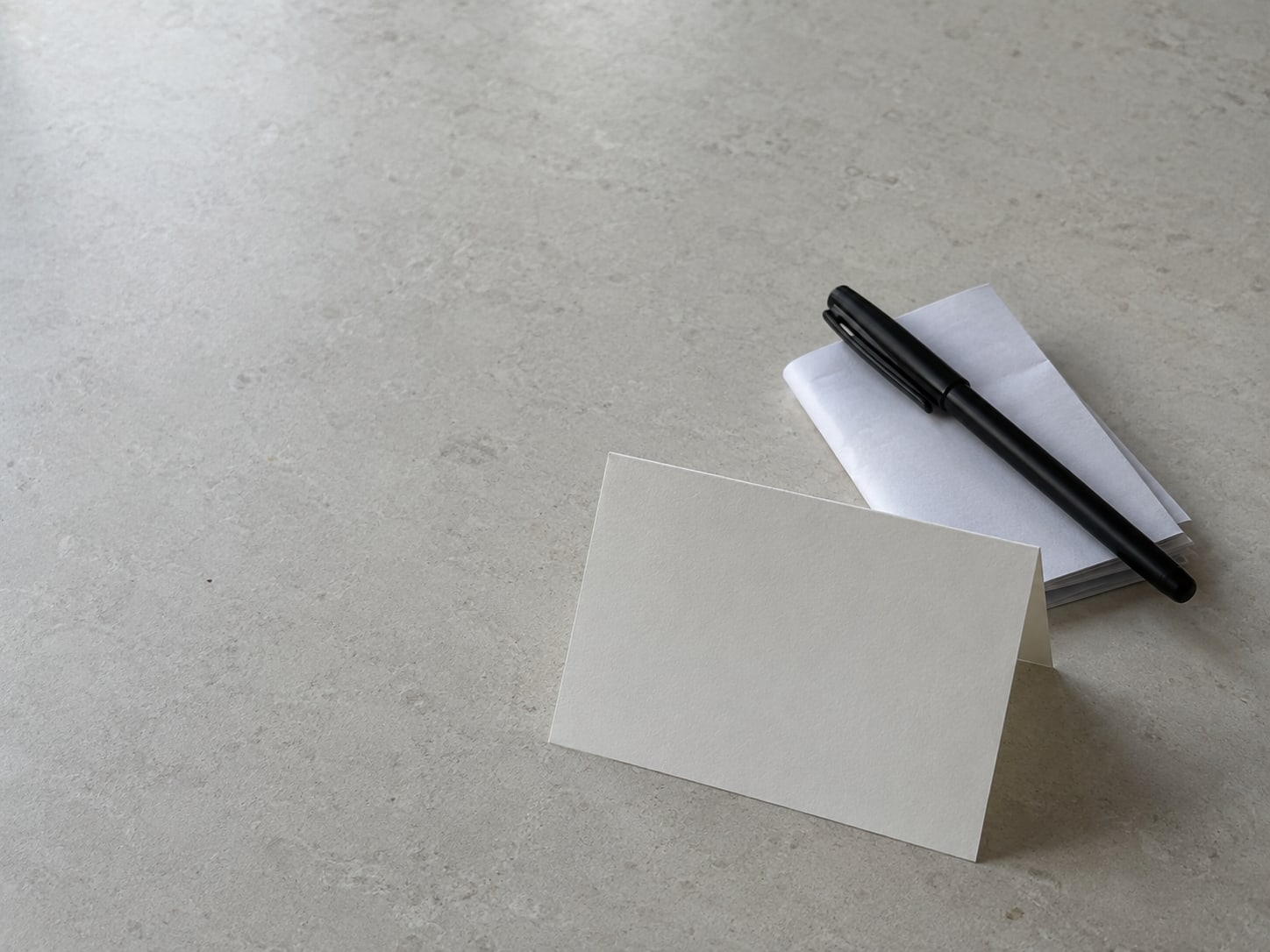 A plain thank-you card and a closed pen resting on a stack of folded receipts.