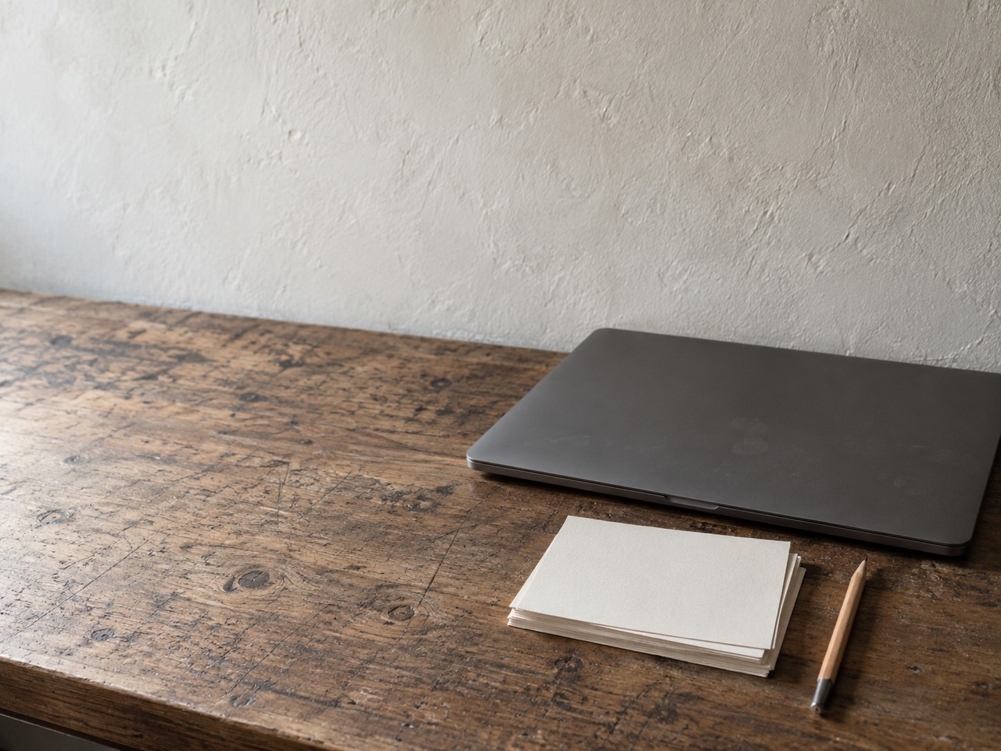 A stack of blank postcards and a pen beside a closed laptop on a shop counter.