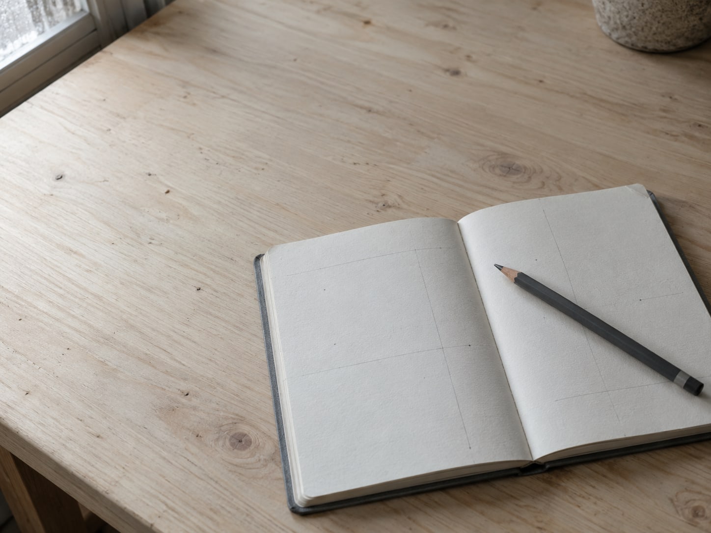 A small notebook open to a half-finished outline sketched in pencil, a pencil resting across the page.