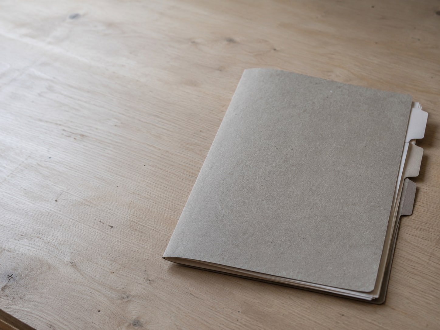 A folder of loose papers with colored tabs sticking out at the edge, sitting on a clean desk.