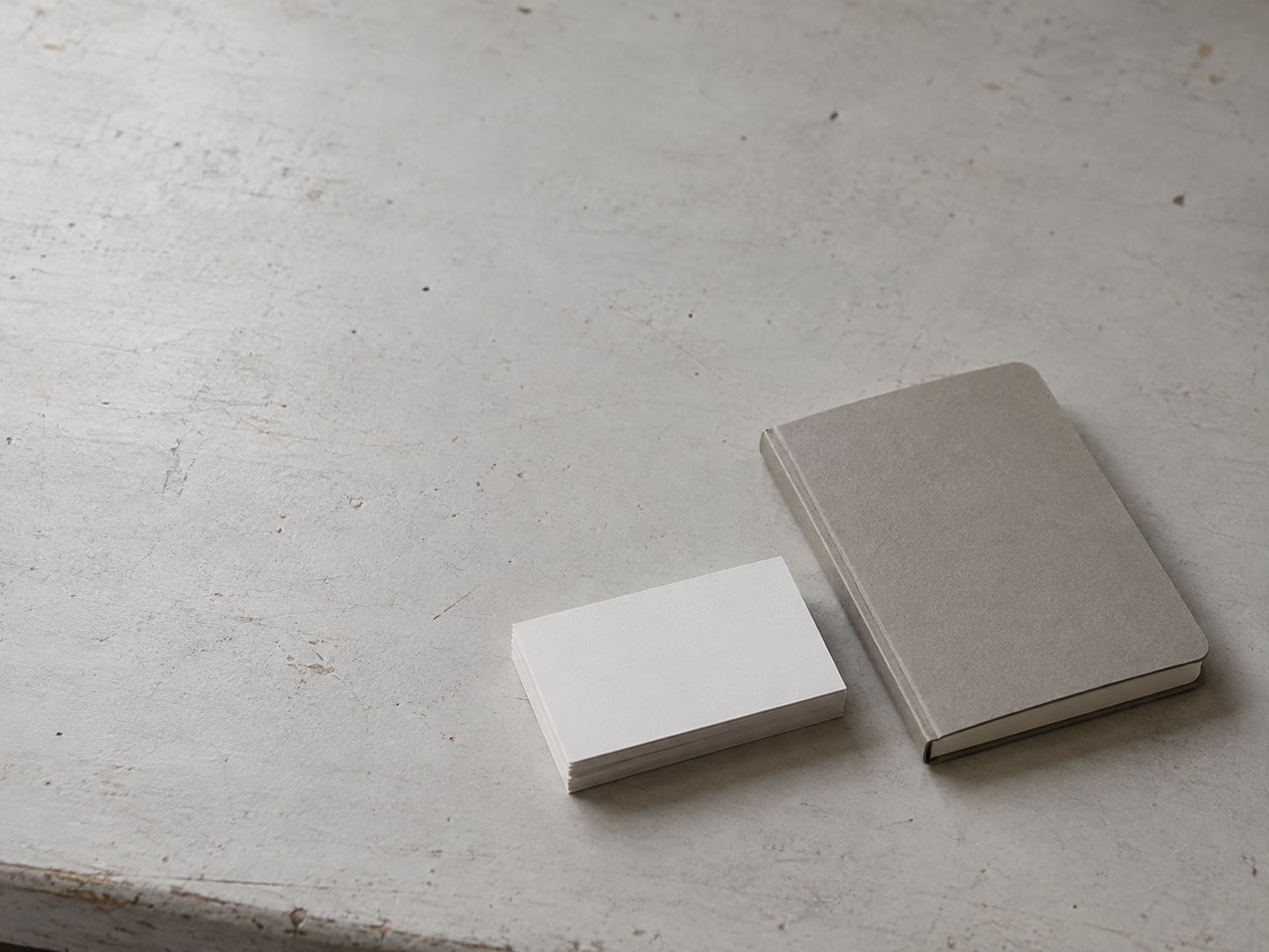 A stack of blank appointment cards beside a small closed notebook on a clean workbench.