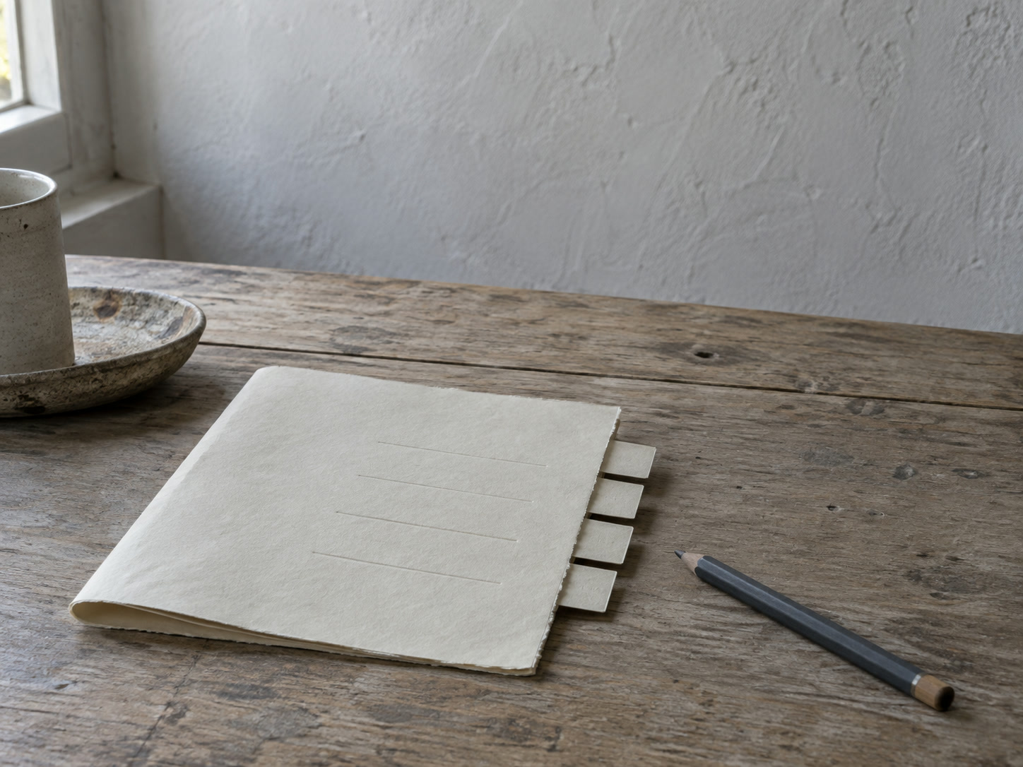 A sheet of paper with a few blank ruled lines and small tabs along its edge, a pencil beside it on a wooden desk.