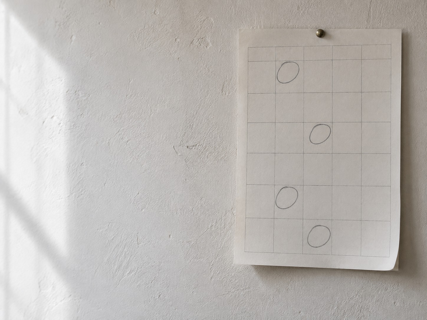 A paper wall calendar with only a few days circled in pencil, most of the month left blank.