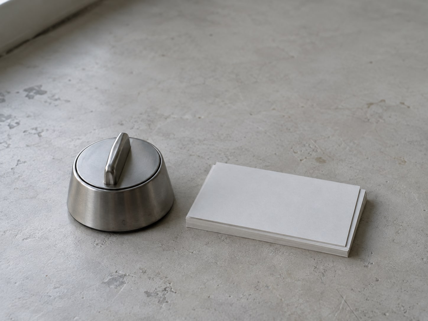 A kitchen timer next to a short stack of blank index cards on a clean countertop.