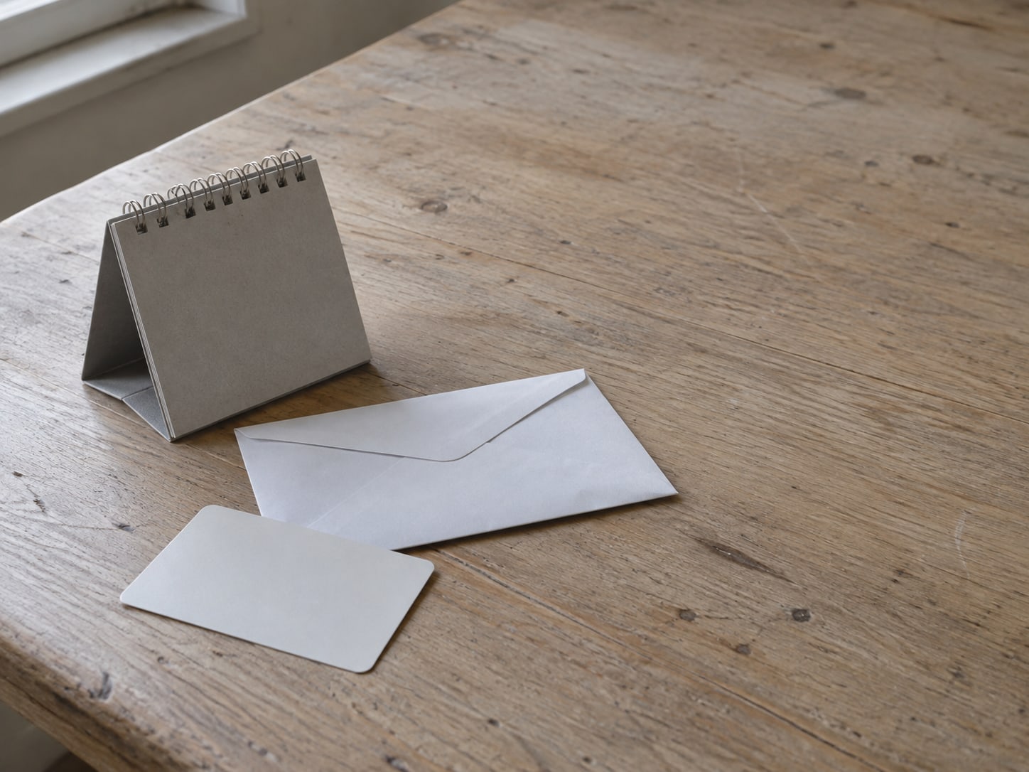 A plain payment card lying face down beside an unopened envelope and a small desk calendar with no markings.