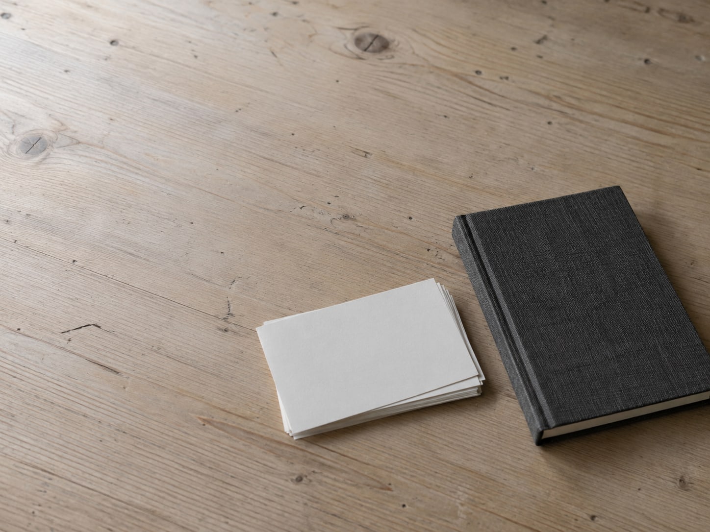 A small stack of blank index cards and a closed notebook on a clean desk surface.