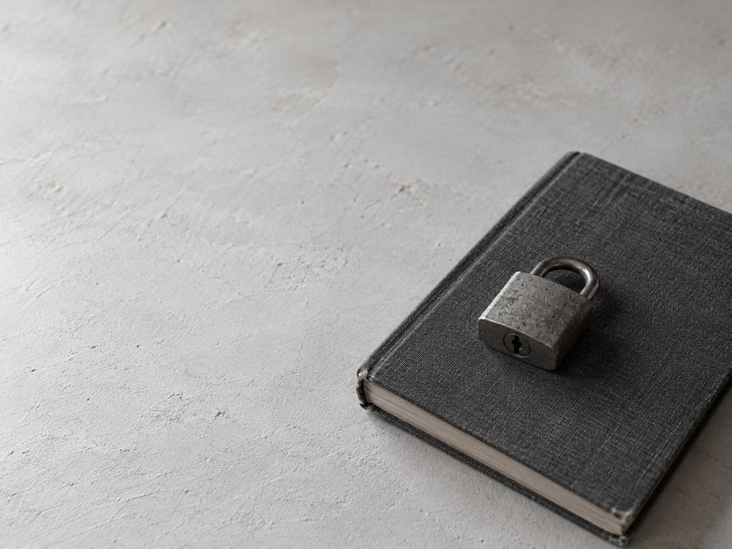 A padlock resting on a closed notebook on a clean desk.