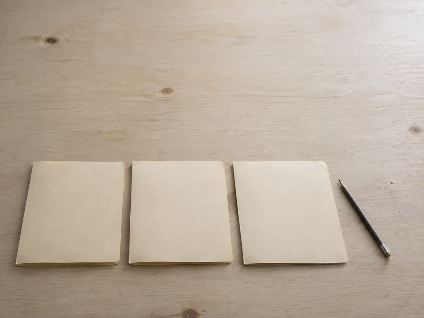 A tidy row of three blank file folders and a pencil on a clean desk.