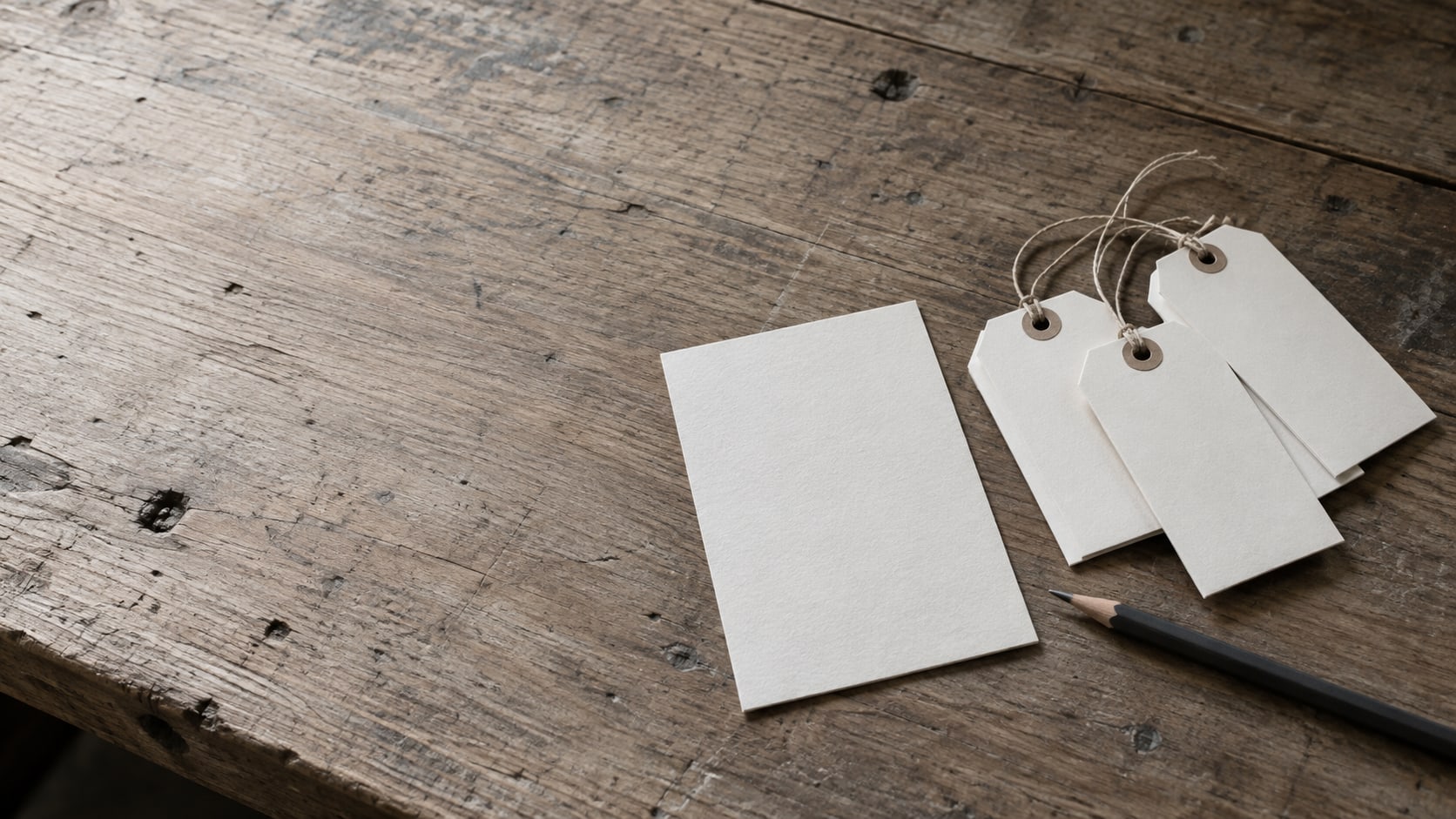 Blank price tags and a blank checklist card laid out on a workshop bench beside a pencil.