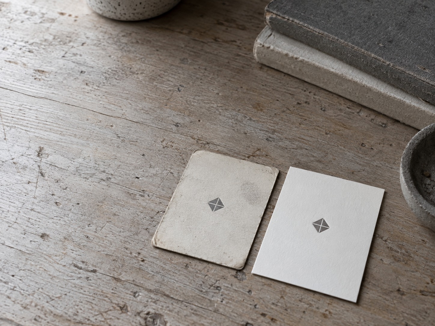 A worn business card beside a newly printed one with the same simple mark, cleaner lines and the same colors.