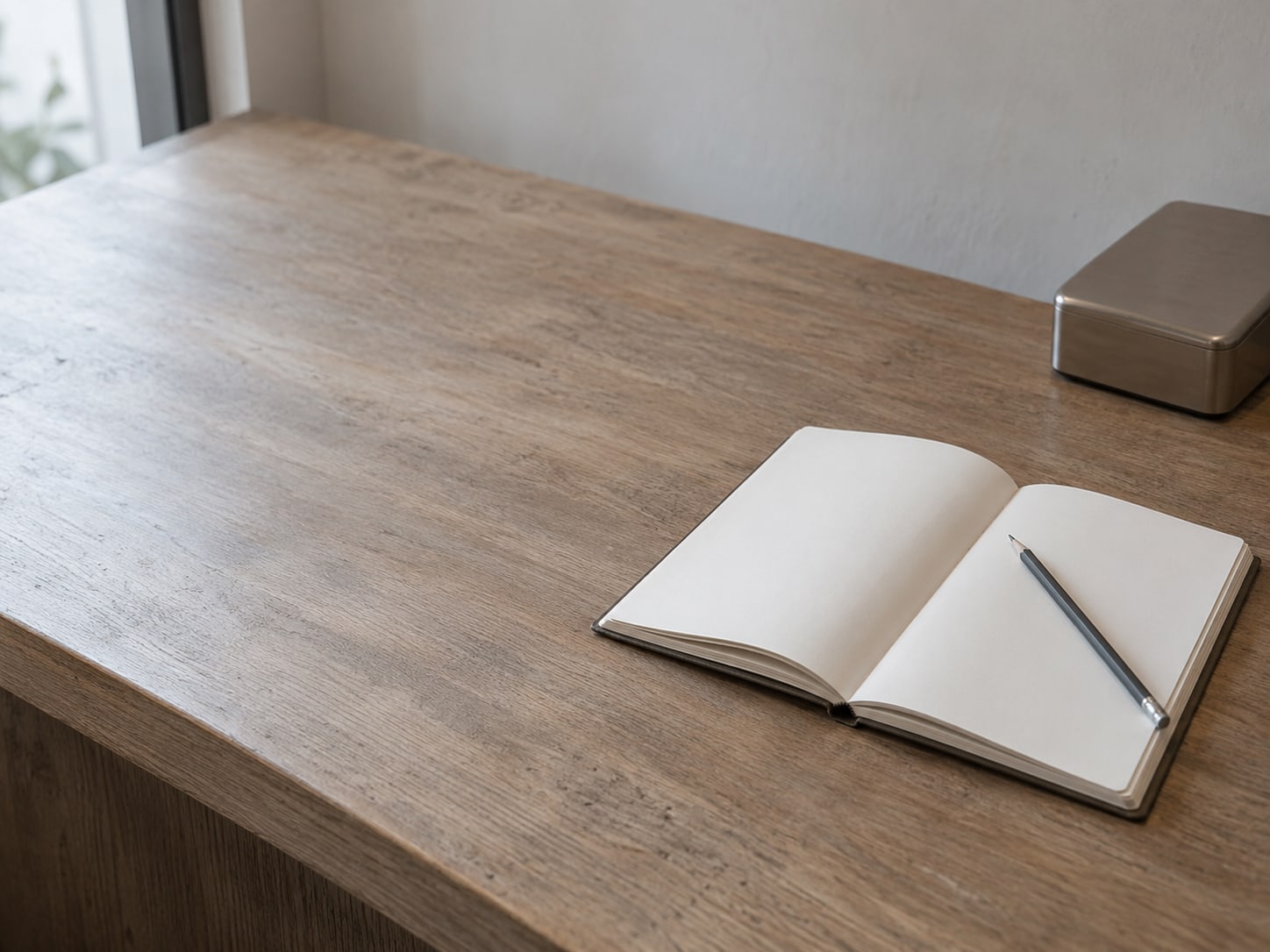 An open appointment book and a pencil on a reception desk beside a closed card reader, with the pages turned to a blank day.