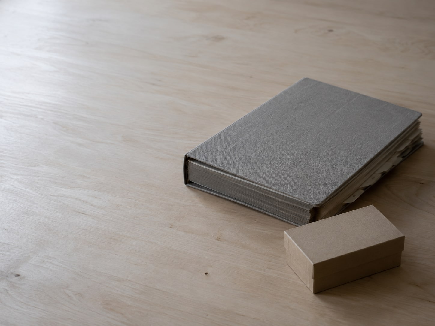 A closed binder with tabbed dividers beside an unopened box of printed business cards.