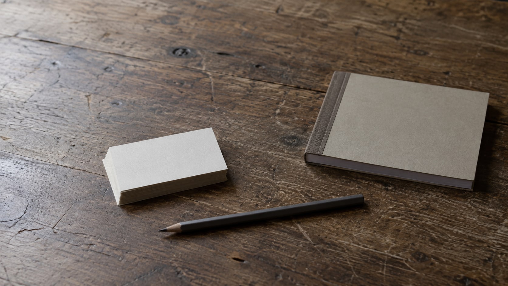 A small stack of blank cards and a pencil beside a closed receipt book on a shop counter.