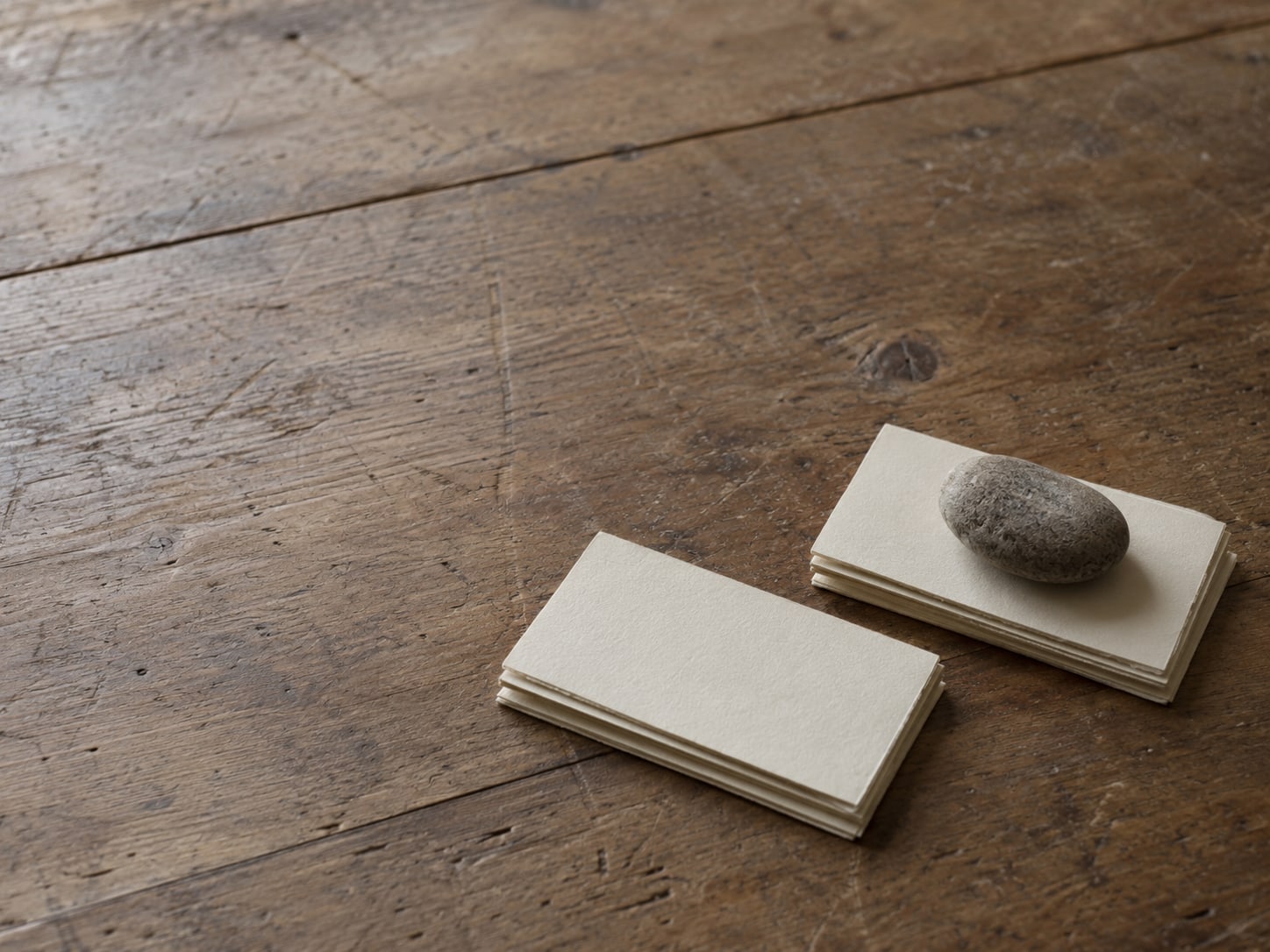Six blank index cards sorted into two neat piles on a desk, with a small paperweight on one pile.