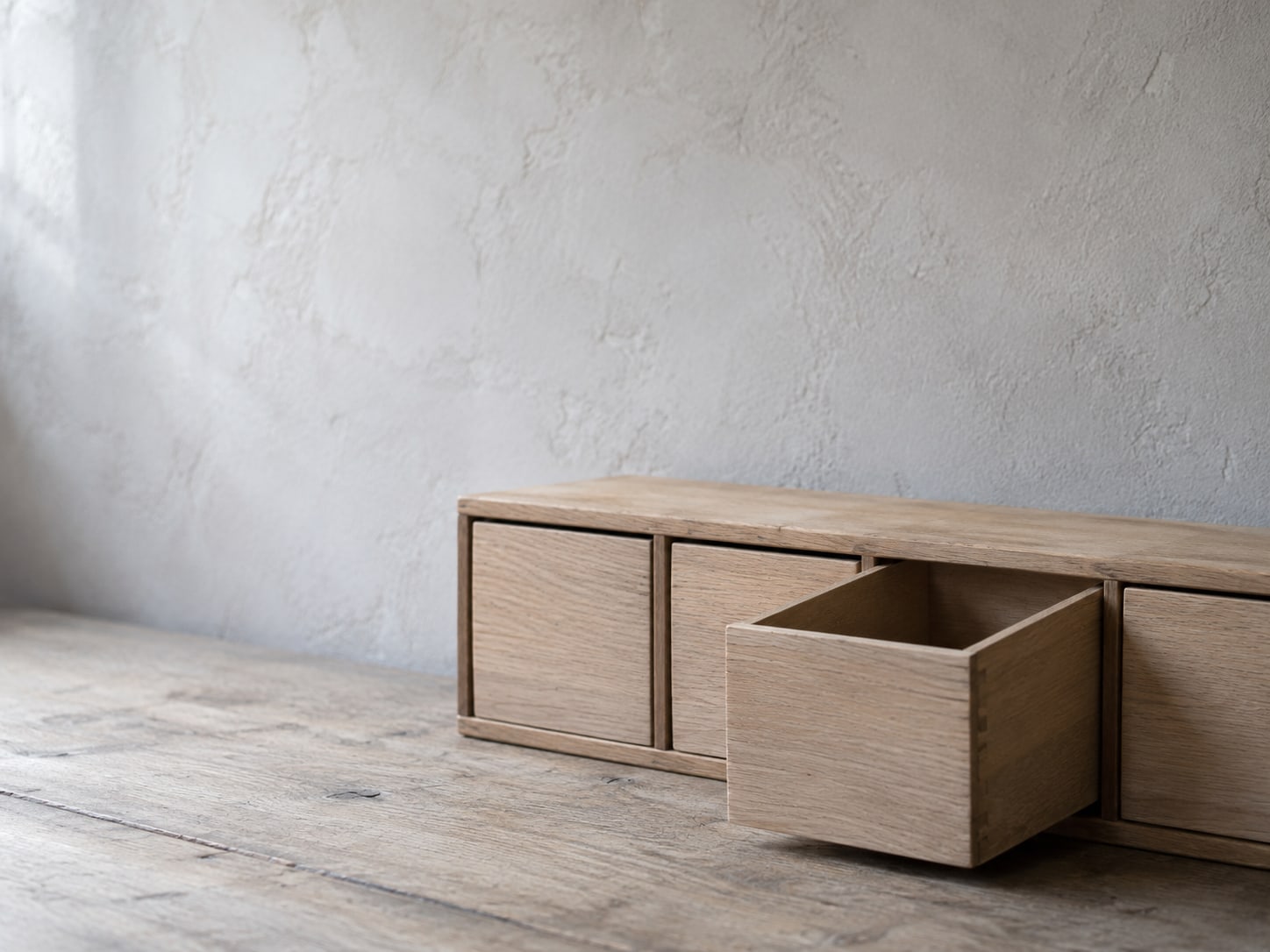 A neat row of identical wooden drawers with one drawer pulled halfway open and left empty.