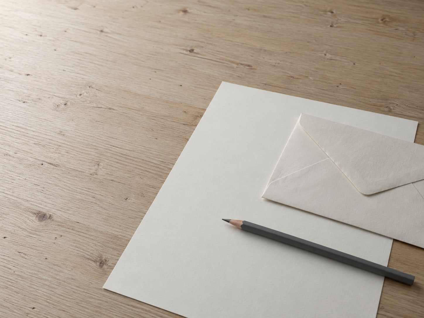 Un solo sobre color crema y un bolígrafo sobre una hoja de papel en blanco, en un escritorio limpio