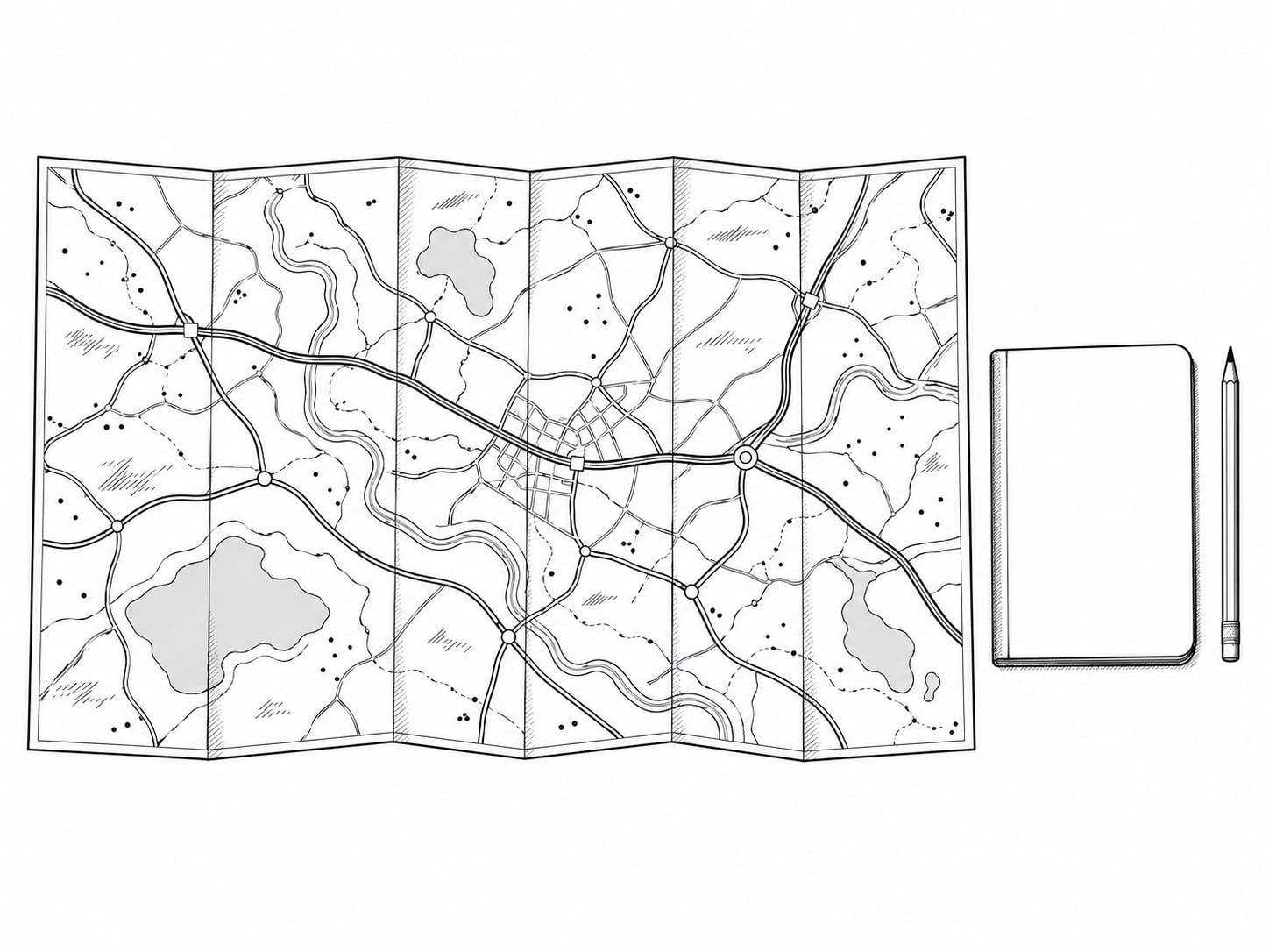 A folded paper road map sitting flat on a table beside a closed notebook and a pencil.