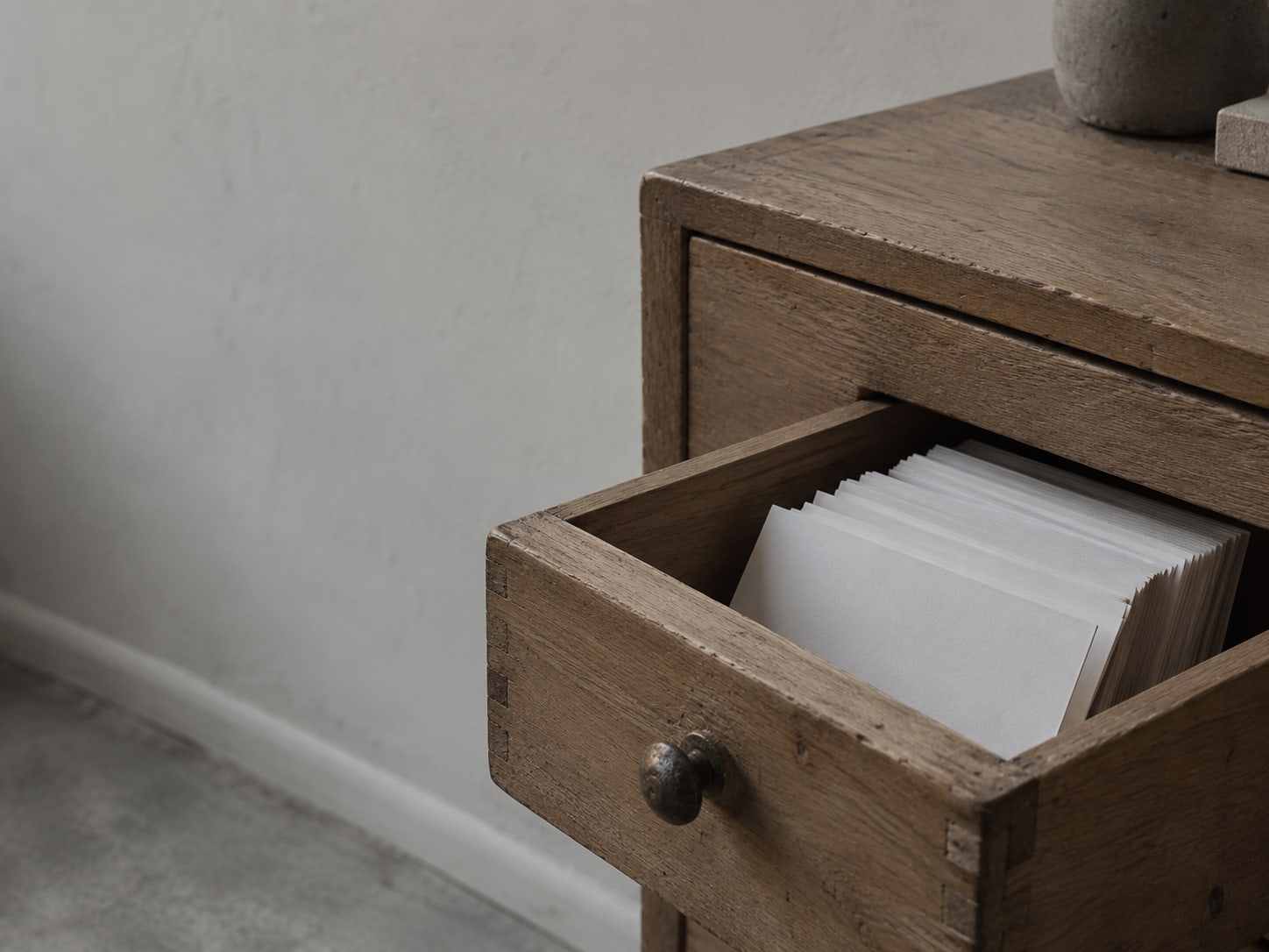 A single wooden drawer pulled open on a small cabinet, holding a row of blank index cards.