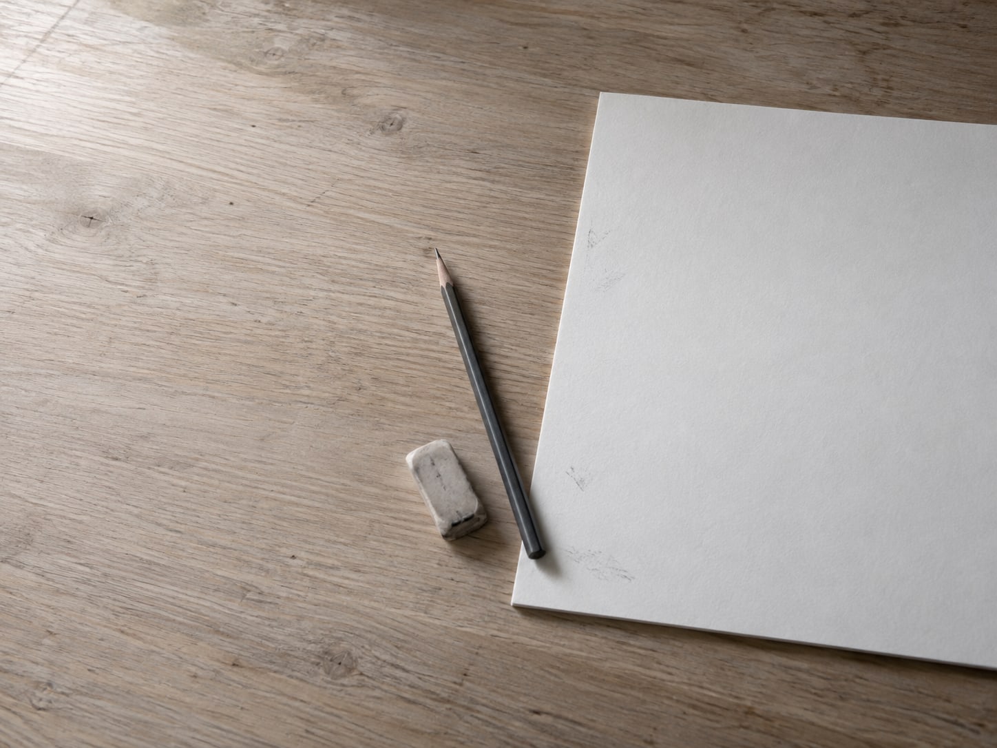 A printed page of blank lines with faint pencil marks in the margin, a pencil and an eraser beside it on a desk.