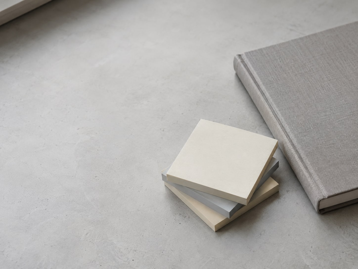 A small stack of blank sticky notes in three colors beside a closed notebook on a clean desk.