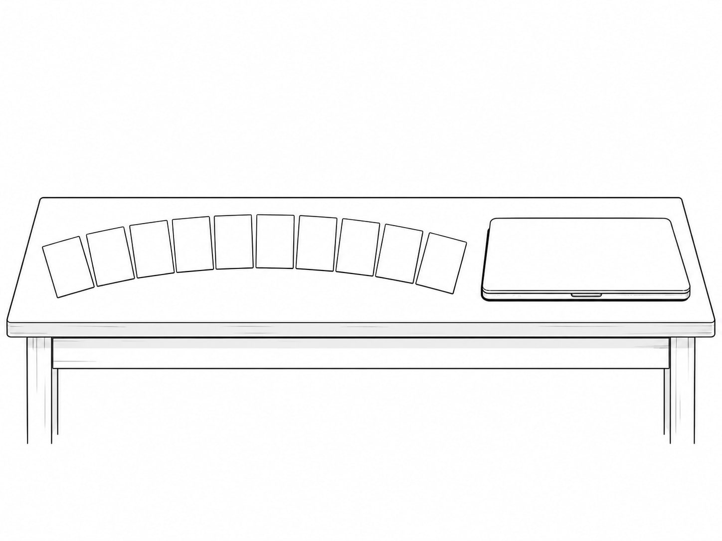 A neat row of ten blank index cards fanned out on a table next to a closed laptop.