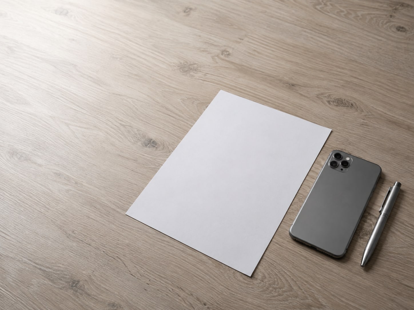 Un smartphone boca abajo junto a un formulario de papel en blanco y una pluma cerrada sobre un escritorio claro.