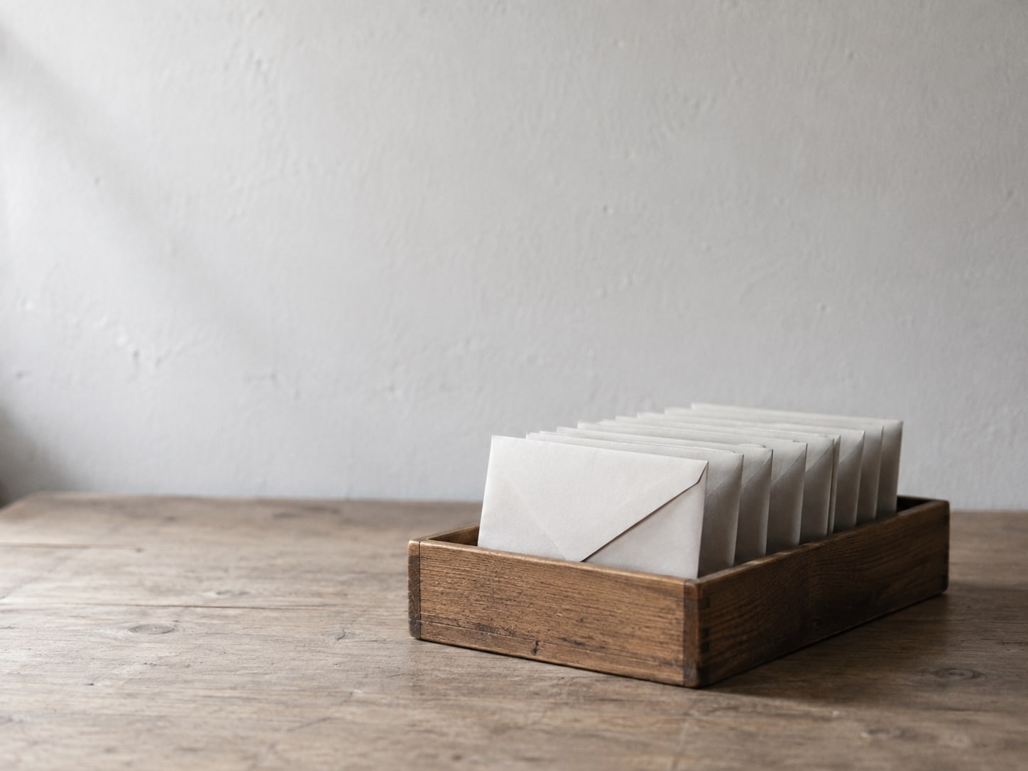 A tidy row of small envelopes standing upright in a wooden tray, each one sealed and unmarked.