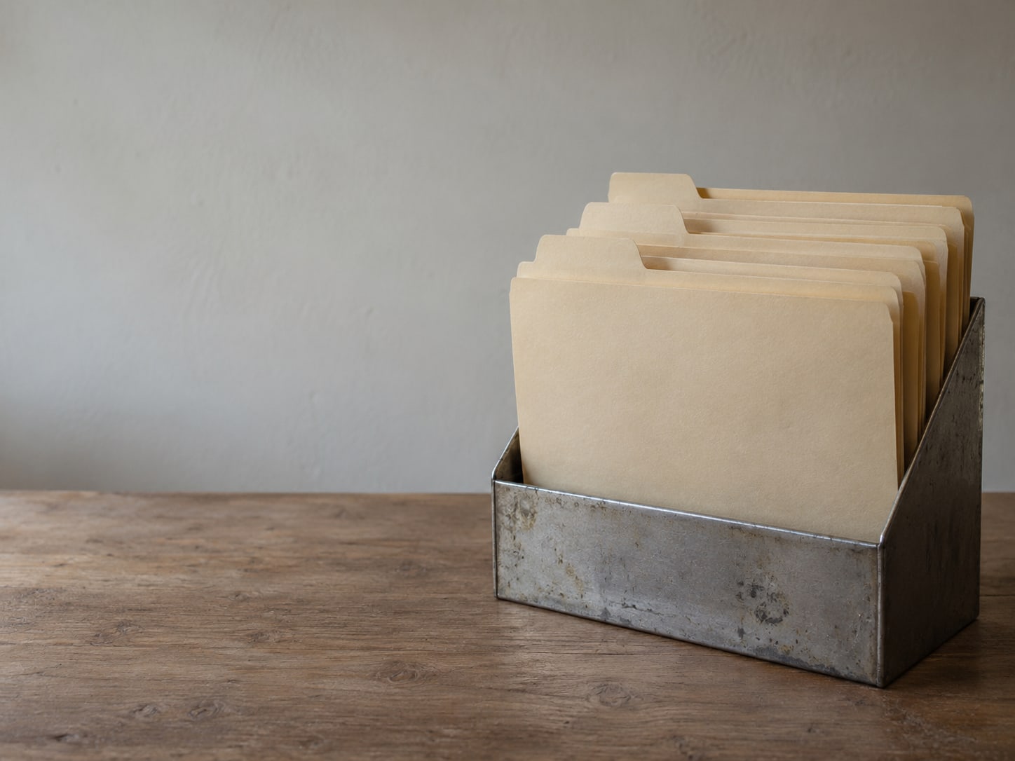 A set of tabbed manila folders standing upright in a desk organizer, all tabs blank.